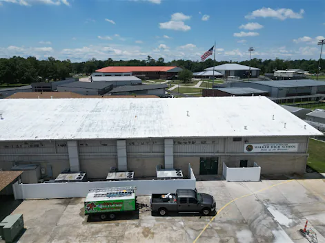 Aerial drone photo of the Walker High School gym in Louisiana after commercial roof cleaning, the metal roof cleaned to an even, light finish.