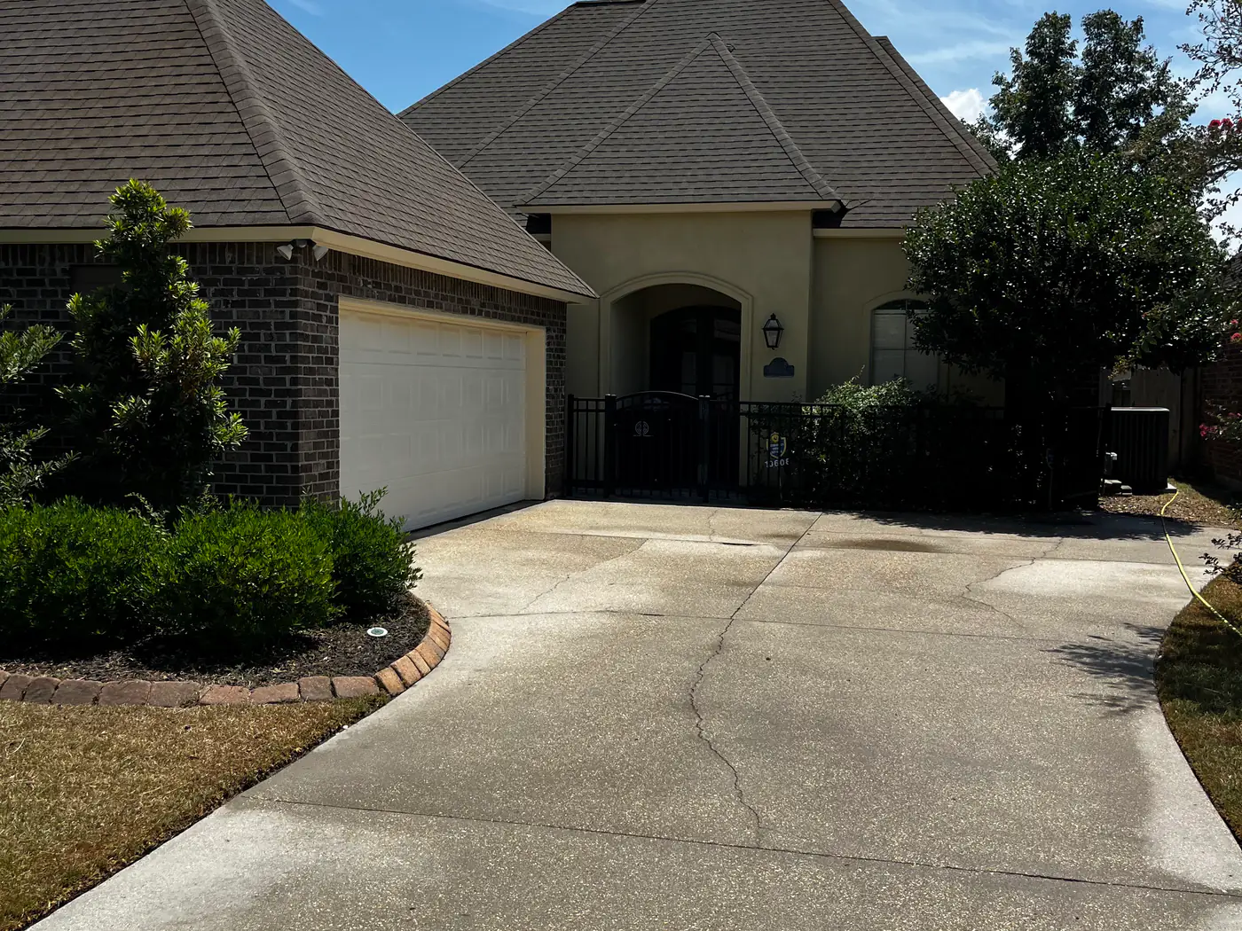 A long, clean residential concrete driveway leading to a brick home.