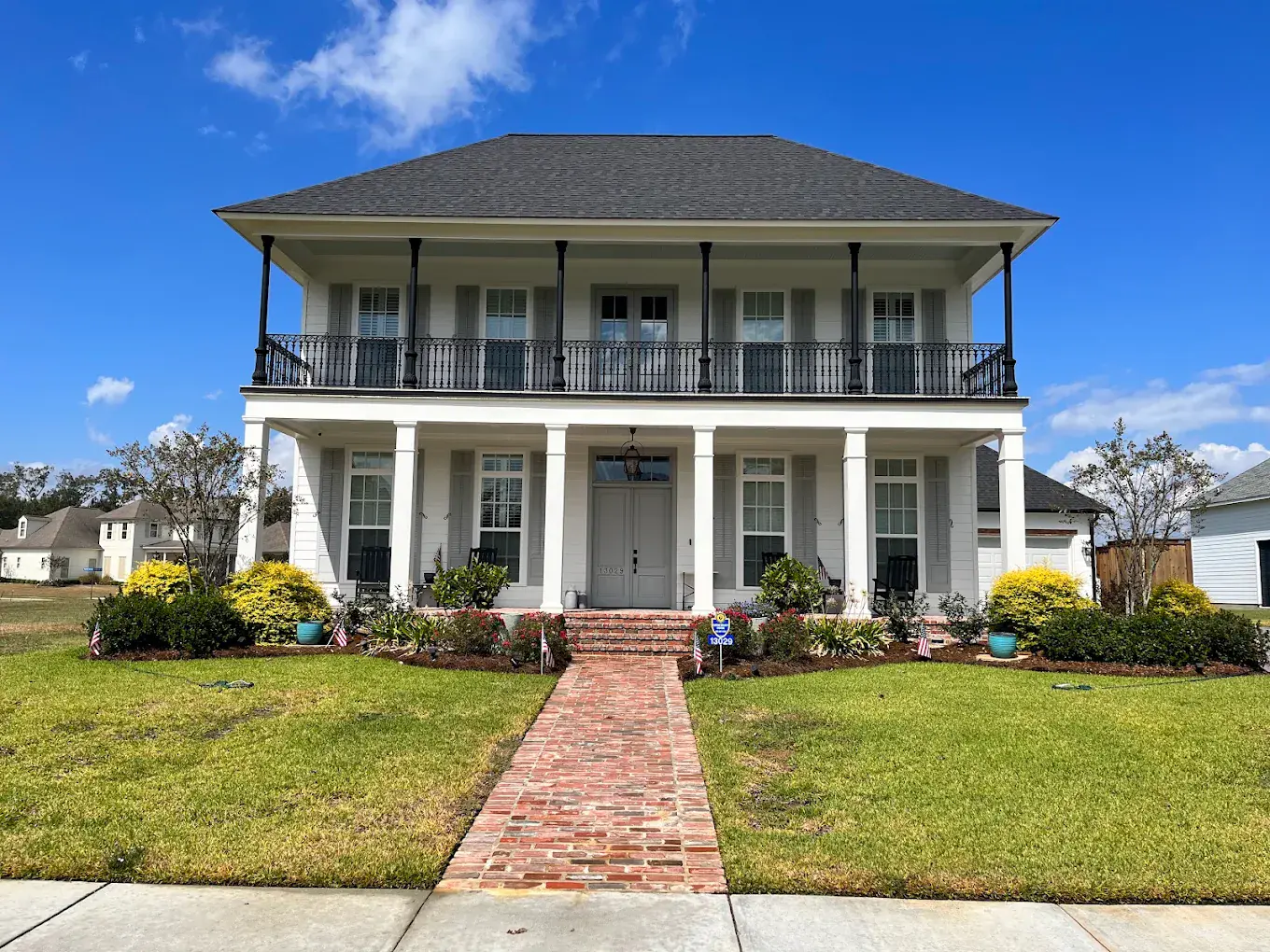 Two-story white home with a double front porch after exterior soft washing, with a freshly cleaned brick walkway leading to the front steps.
