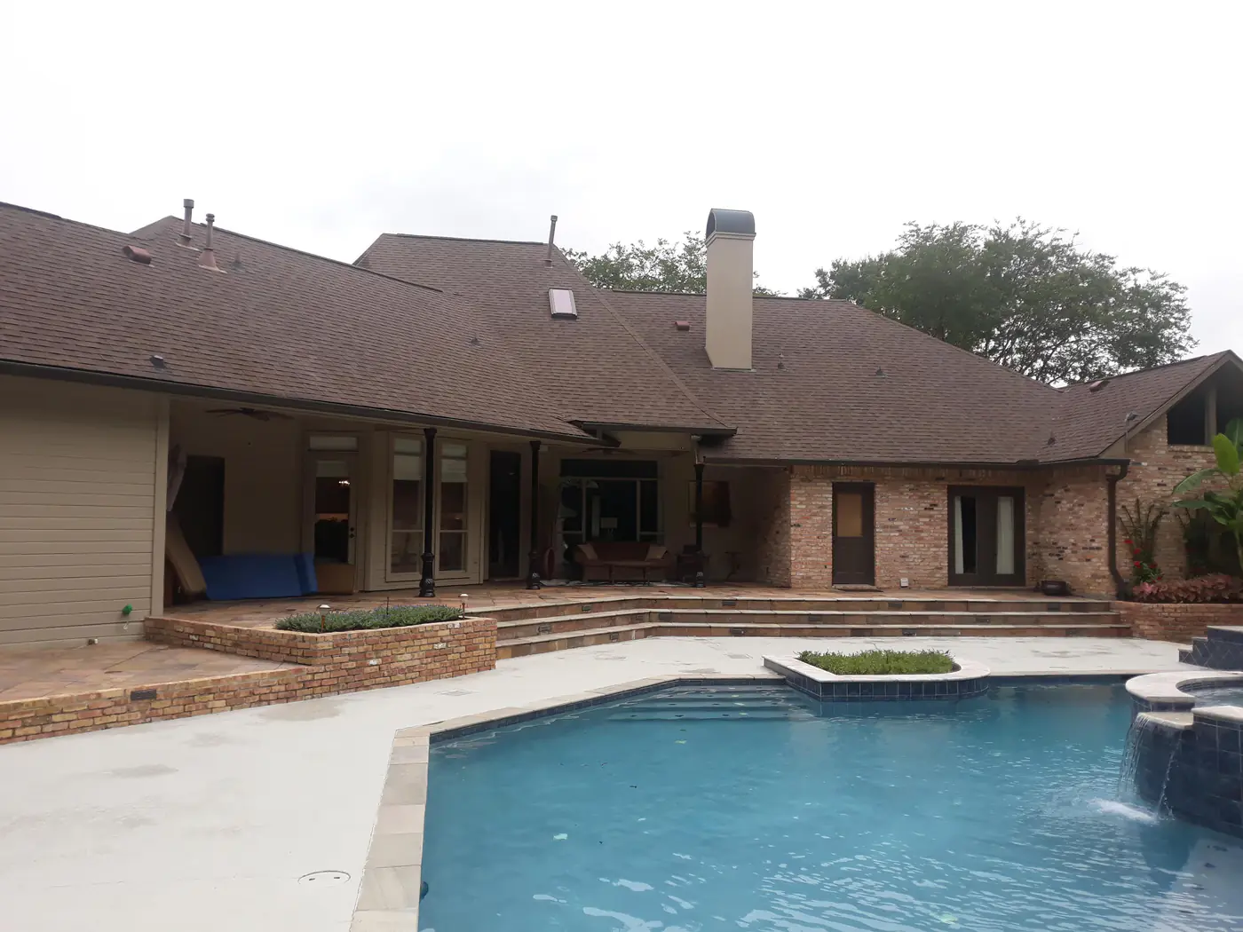 A large clean concrete pool deck behind a home after soft washing.
