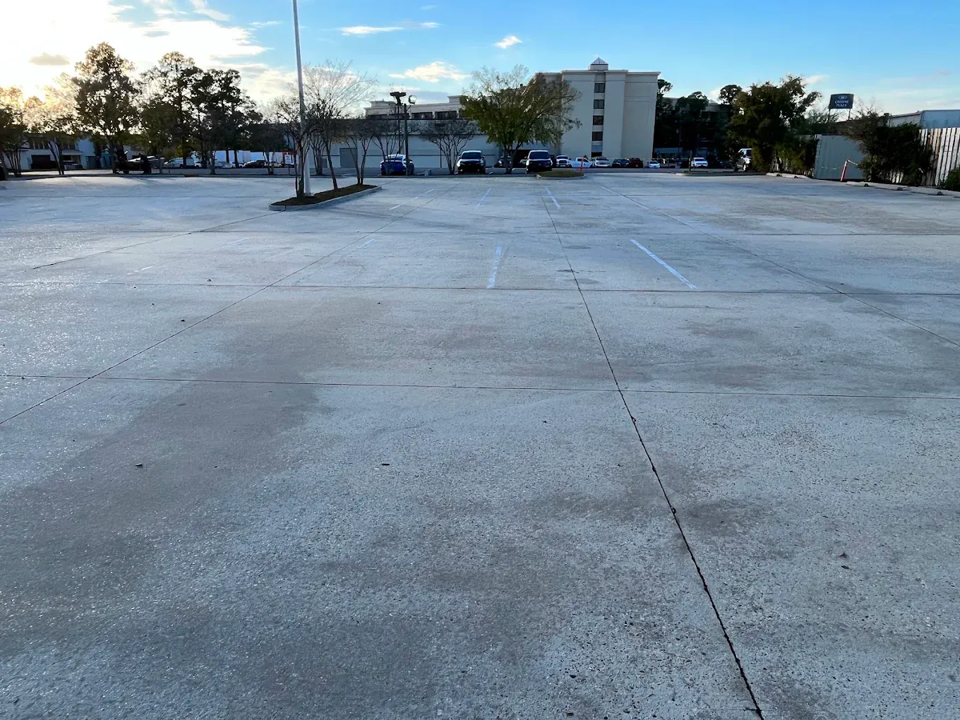 A large commercial concrete parking lot after cleaning, the surface an even, uniform light grey.